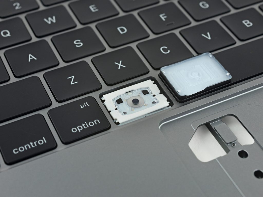 A MacBook Butterfly keyboard with a keycap off revealing the inner workings of the key