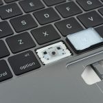 A MacBook Butterfly keyboard with a keycap off revealing the inner workings of the key